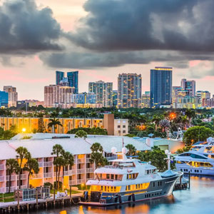 The image shows a cityscape with skyscrapers, residential buildings, and yachts docked in a marina