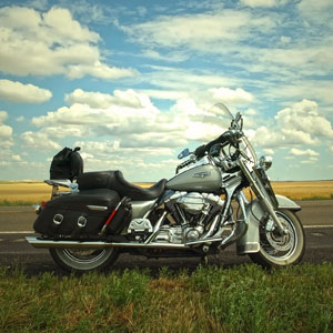 A motorcycle parked on the roadside, showcasing its sleek design against a backdrop of greenery - Charles Injury Law.