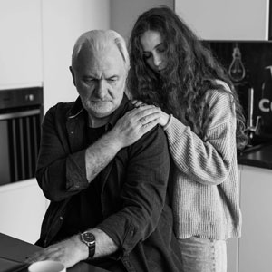 A man and woman are seated at a kitchen table, engaged in conversation - Charles Injury Law.