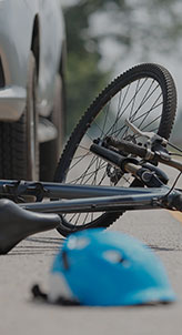 A bicycle is lying on its side on a road, with a blue helmet nearby. 