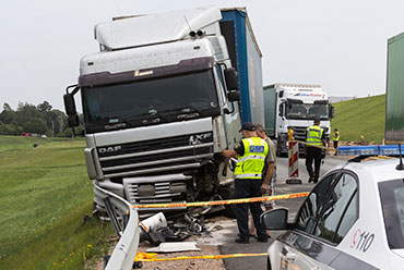 A truck is seen crashed on the roadside, with debris scattered around