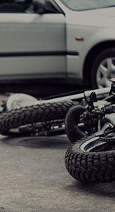 A motorcycle has been involved in an accident. It is lying on its side on the road, with damage to its wheels